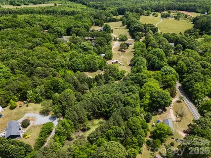 an aerial view of residential house with outdoor space and trees all around