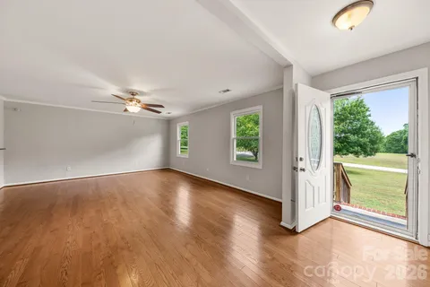 an empty room with wooden floor and windows