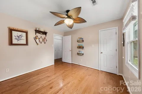 an empty room with wooden floor and ceiling fan