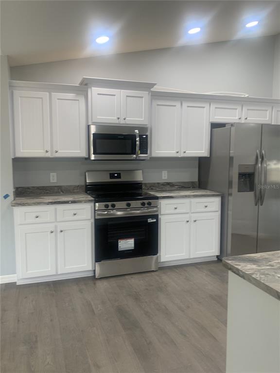 16201 Crider Road Brooksville, FL 34614 - Photo 4 of 18 a kitchen with granite countertop white cabinets and stainless steel appliances