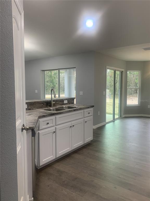 16201 Crider Road Brooksville, FL 34614 - Photo 5 of 18 a kitchen with stainless steel appliances granite countertop a stove a sink and white cabinets with wooden floor
