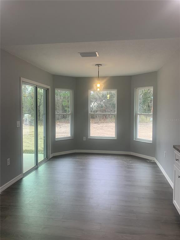 16201 Crider Road Brooksville, FL 34614 - Photo 6 of 18 an empty room with wooden floor and windows