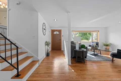 a living room with furniture a large window and wooden floor