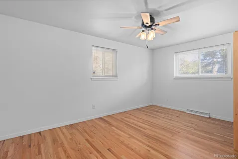 an empty room with wooden floor and ceiling fan