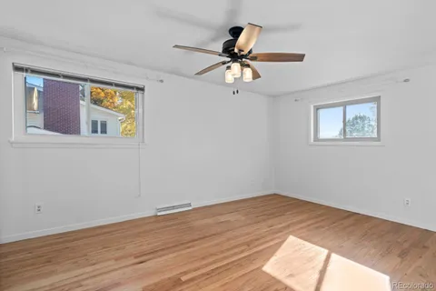 a view of empty room with wooden floor and fan