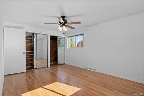 a view of empty room with wooden floor and fan