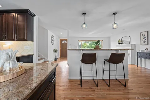 a kitchen with stainless steel appliances granite countertop a table chairs and a refrigerator