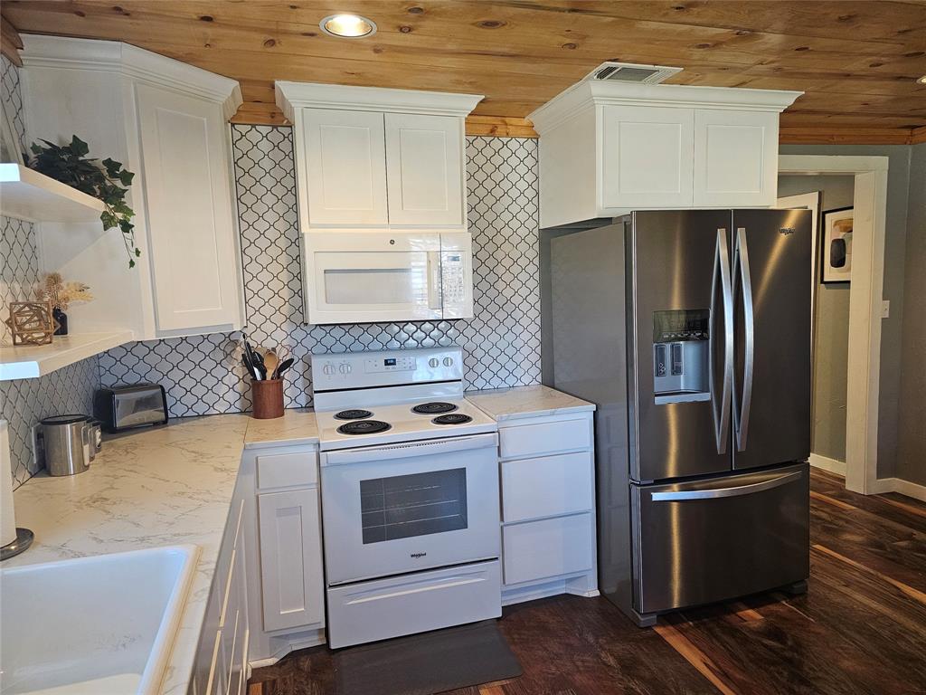 165 Elmwood Road Whitney, TX 76692 - Photo 13 of 28 Kitchen featuring white appliances, white cabinets, dark wood-type flooring, wood ceiling, and open shelves