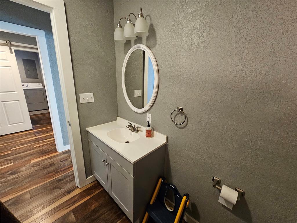 165 Elmwood Road Whitney, TX 76692 - Photo 15 of 28 Bathroom with vanity, washer / dryer, dark wood-style flooring, a textured wall, and electric panel