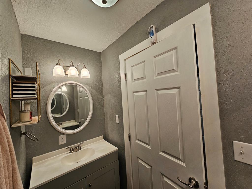 165 Elmwood Road Whitney, TX 76692 - Photo 16 of 28 Bathroom featuring a textured wall, a textured ceiling, and vanity