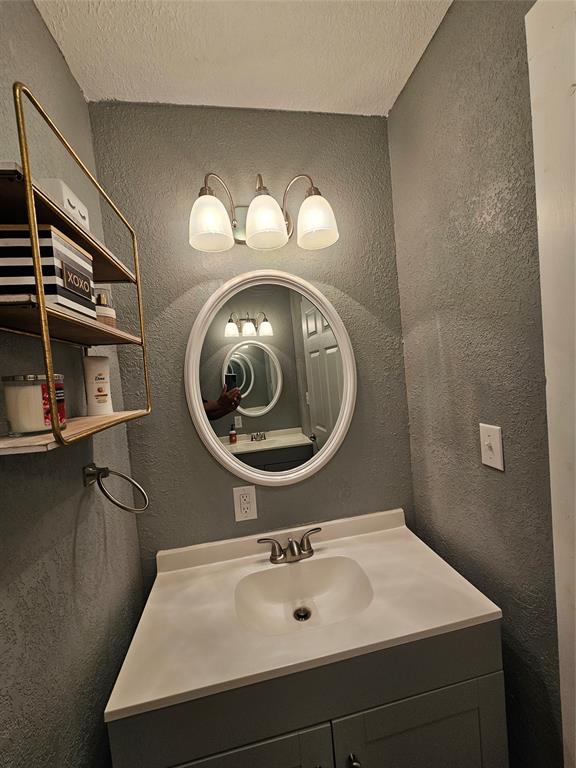 165 Elmwood Road Whitney, TX 76692 - Photo 19 of 28 Bathroom featuring a textured wall, vanity, and a textured ceiling