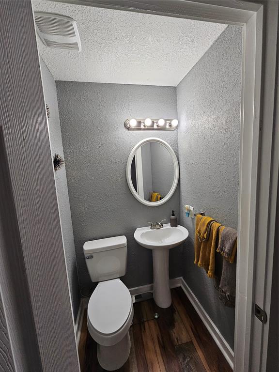 165 Elmwood Road Whitney, TX 76692 - Photo 27 of 28 Half bathroom with a textured wall, dark wood finished floors, and a textured ceiling