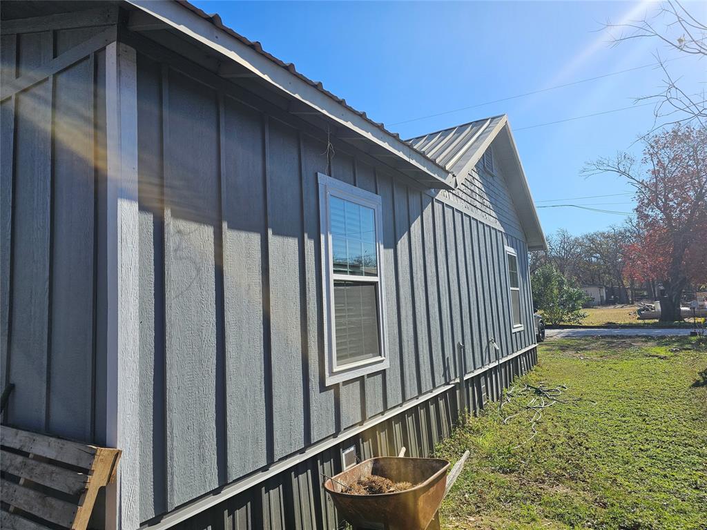 165 Elmwood Road Whitney, TX 76692 - Photo 4 of 28 View of home's exterior featuring board and batten siding, a yard, and a metal roof