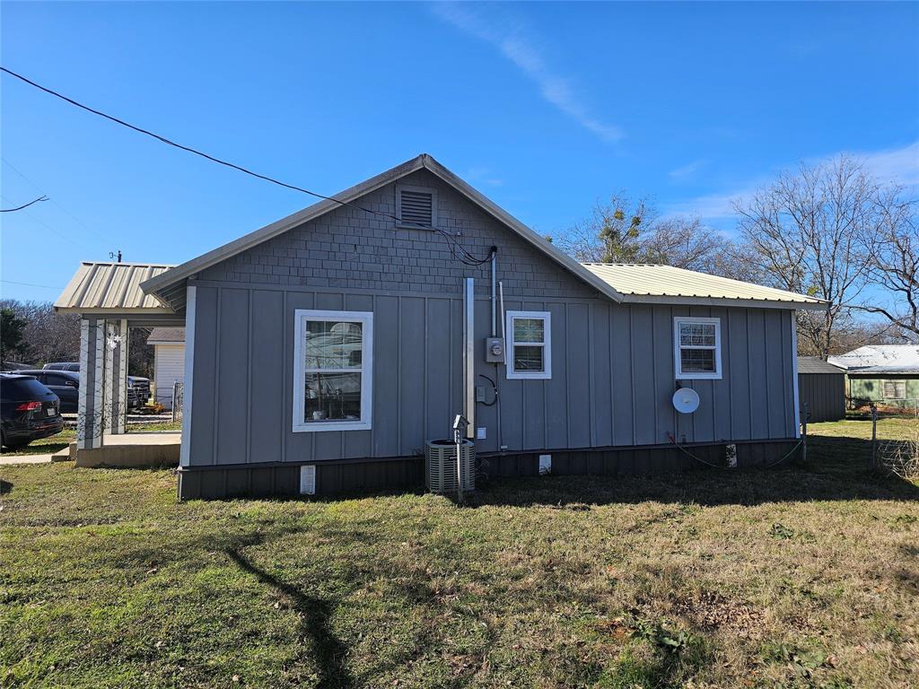 165 Elmwood Road Whitney, TX 76692 - Photo 5 of 28 View of property exterior featuring board and batten siding, a metal roof, and a lawn