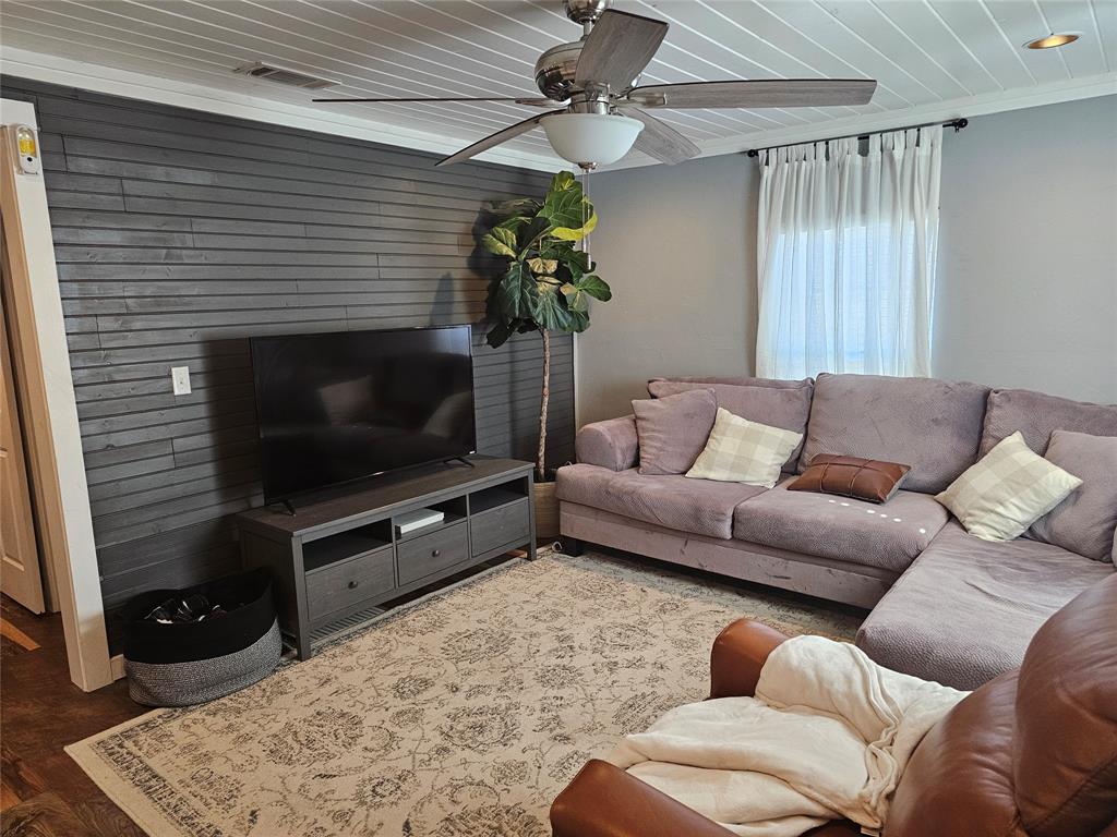 165 Elmwood Road Whitney, TX 76692 - Photo 8 of 28 Living area featuring ceiling fan, wood walls, and wood finished floors