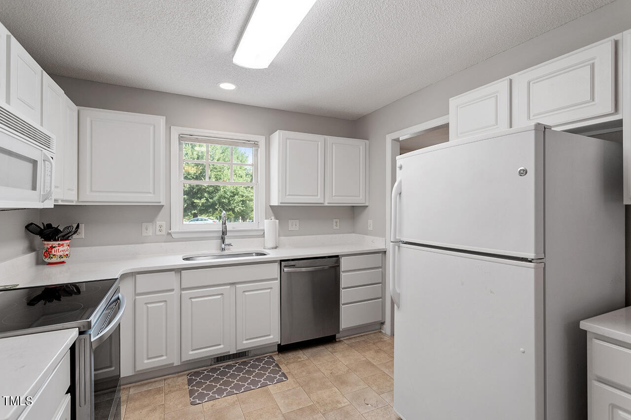 2108 Cedarbluff Court Raleigh, NC 27615 - Photo 13 of 38 a white refrigerator freezer sitting in a kitchen with white cabinets