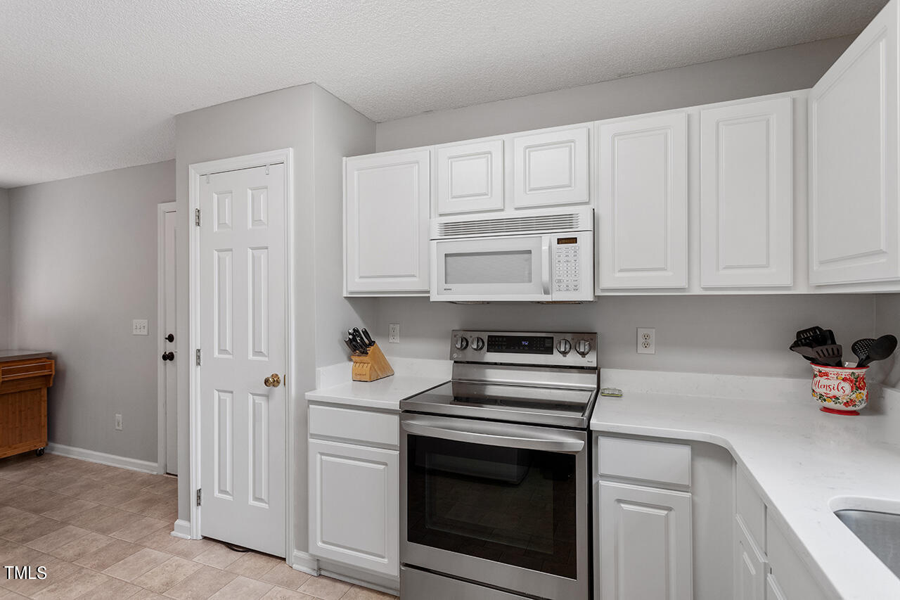 2108 Cedarbluff Court Raleigh, NC 27615 - Photo 14 of 38 a kitchen with white cabinets and appliances