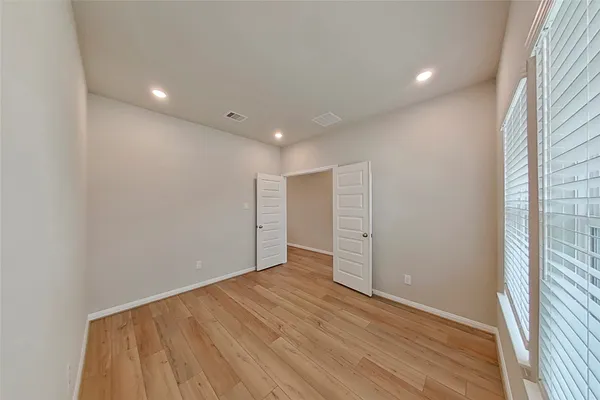 an empty room with wooden floor and windows