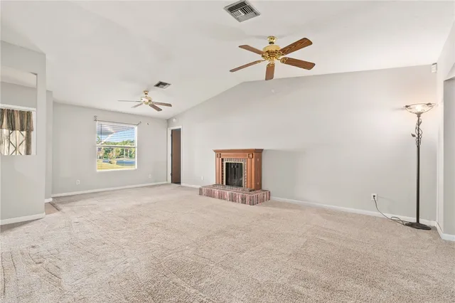 an empty room with ceiling fan and windows