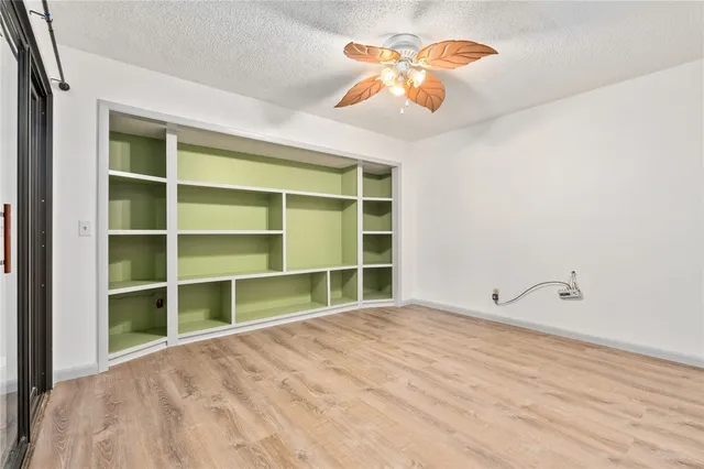 a view of an empty room with a window and cabinet