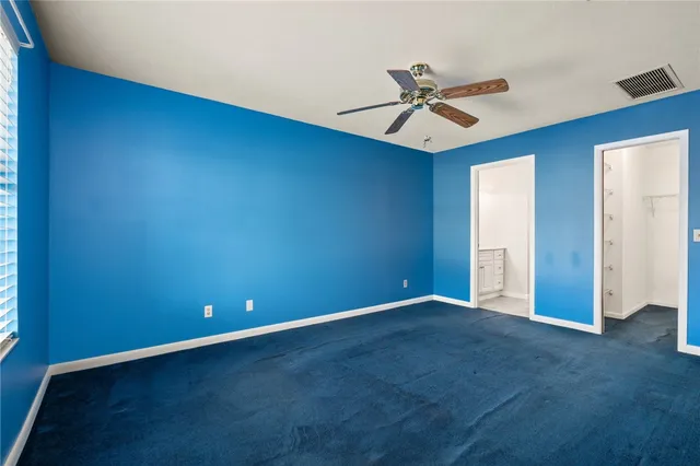 an empty room with closet and a ceiling fan