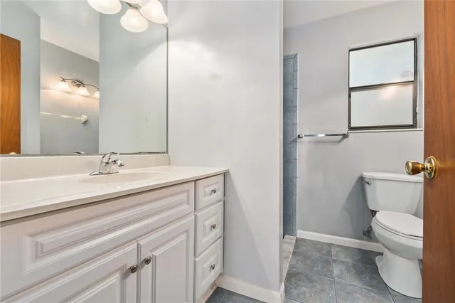 a bathroom with a granite countertop sink a toilet and a mirror