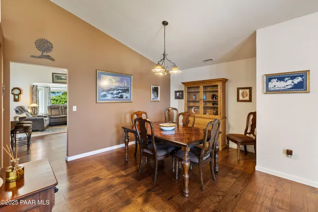 a dining room with wooden floor a chandelier a wooden table and chairs