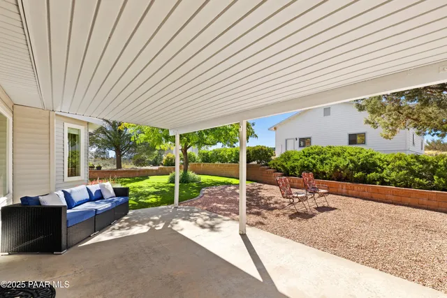 a view of a patio with table and chairs near a barbeque