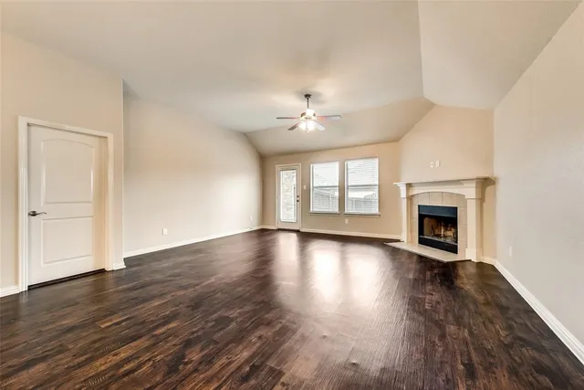 an empty room with wooden floor fireplace and windows