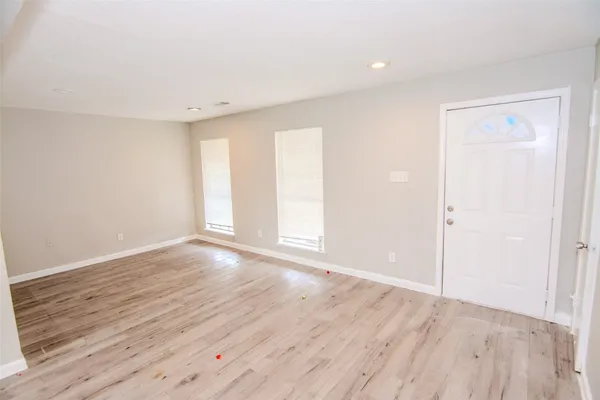 a view of an empty room with wooden floor and a window