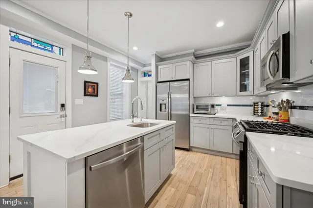 a kitchen that has a lot of white cabinets and stainless steel appliances