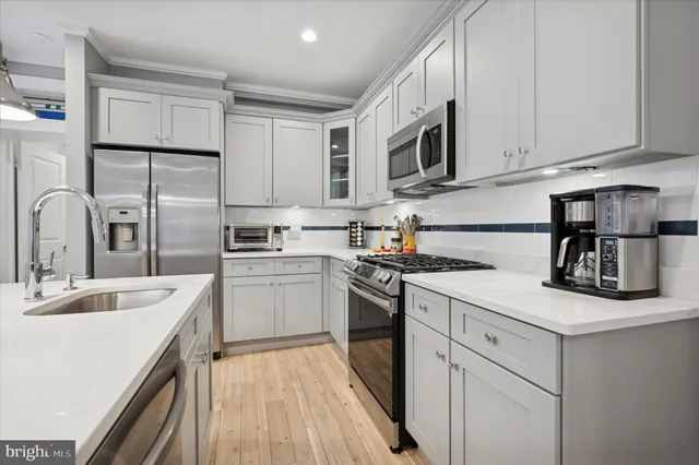 a kitchen with stainless steel appliances granite countertop a sink stove refrigerator and cabinets