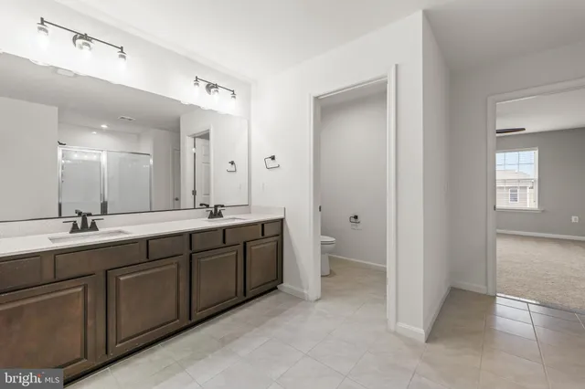 a spacious bathroom with a double vanity sink a mirror and a toilet