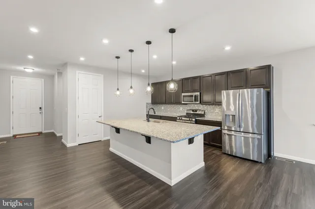 a kitchen with stainless steel appliances granite countertop a large stove a refrigerator a sink and a oven with wooden floor