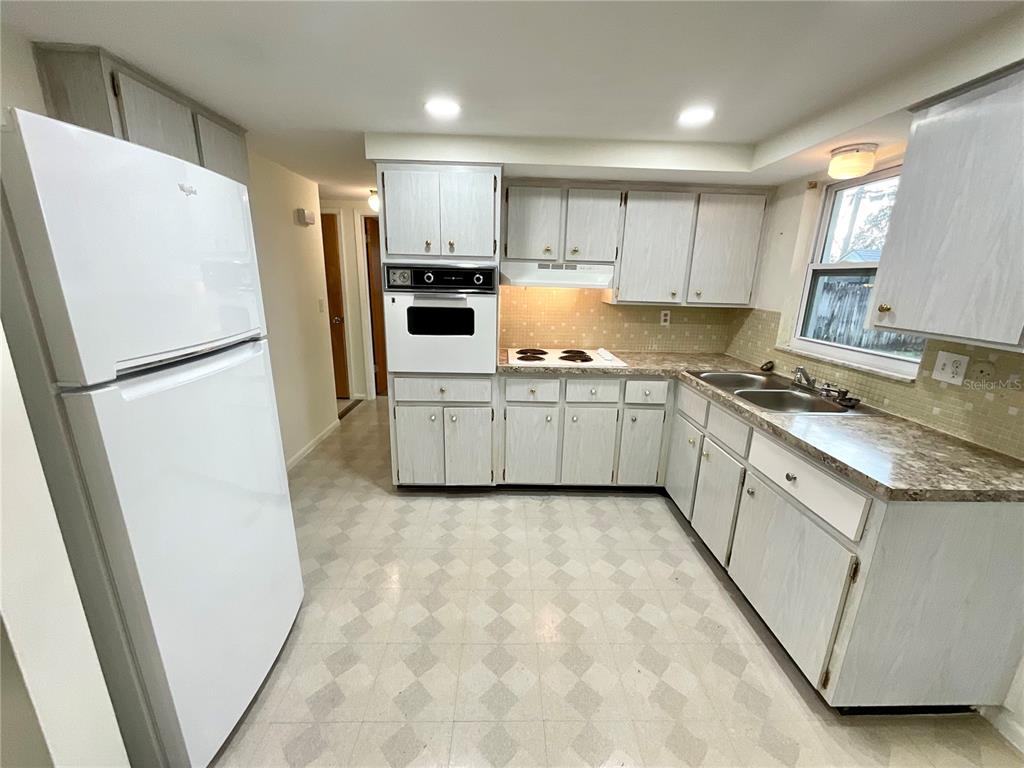 4810 Flora Avenue Holiday, FL 34690 - Photo 4 of 14 a kitchen with white cabinets a refrigerator a sink a stove a microwave and a refrigerator