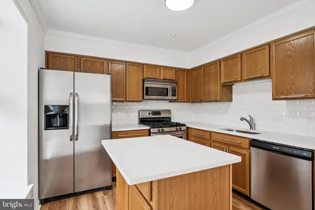 a kitchen with stainless steel appliances a sink a stove a refrigerator cabinets and a counter top space