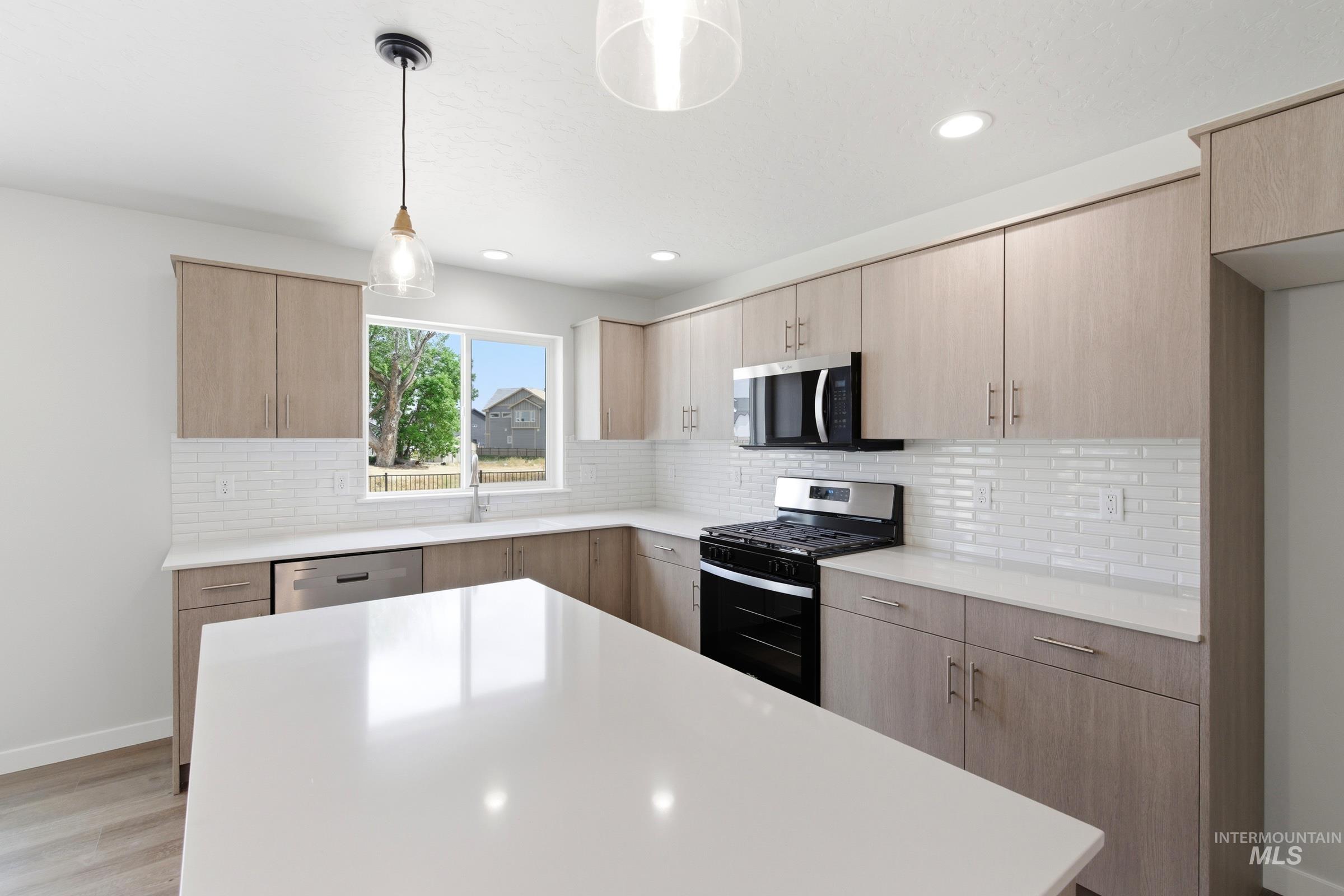 12829 Decatur Street Nampa, ID 83651 - Photo 6 of 33 Contemporary kitchen featuring light wood-finish cabinetry, white countertops, and a white subway tile backsplash