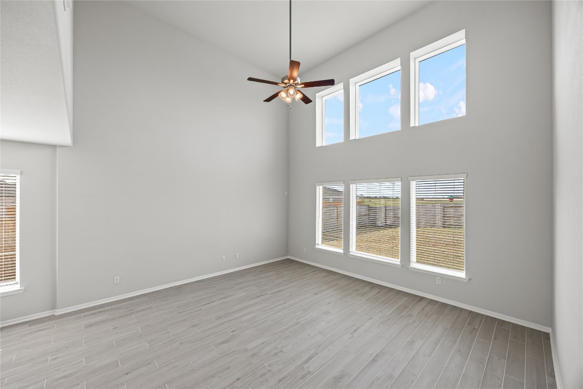 648 Canadian Trail Dayton, TX 77535 - Photo 13 of 37 an empty room with wooden floor ceiling fan and windows