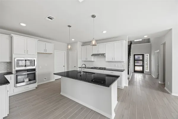 a large kitchen with stainless steel appliances granite countertop a stove a sink and a refrigerator