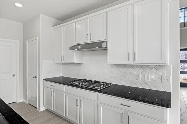 a kitchen with white cabinets and sink
