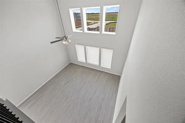 a view of an empty room with wooden floor and windows