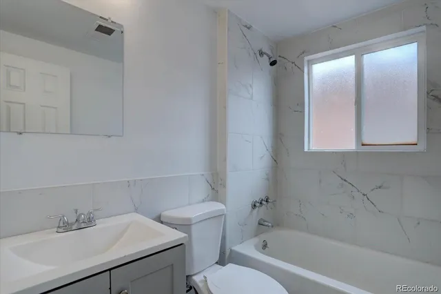 a bathroom with a bathtub shower sink vanity and toilet
