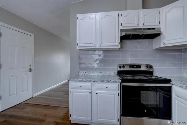 a kitchen with granite countertop white cabinets and appliances
