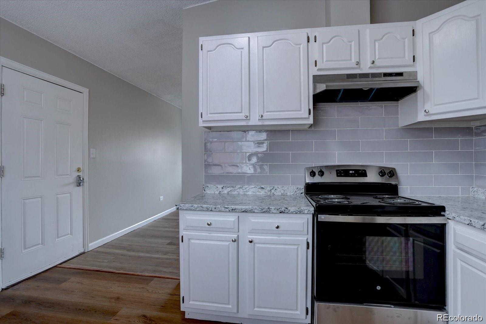 2938 Eliot Circle, Unit 2 Westminster, CO 80030 - Photo 16 of 28 a kitchen with granite countertop white cabinets and appliances