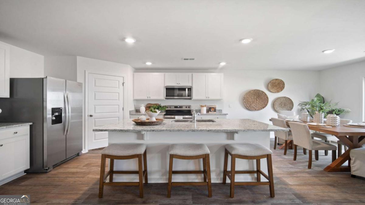 149 Timber Road Statesboro, GA 30458 - Photo 2 of 42 a kitchen with stainless steel appliances granite countertop a stove top oven a refrigerator a dining table and chairs with wooden floor