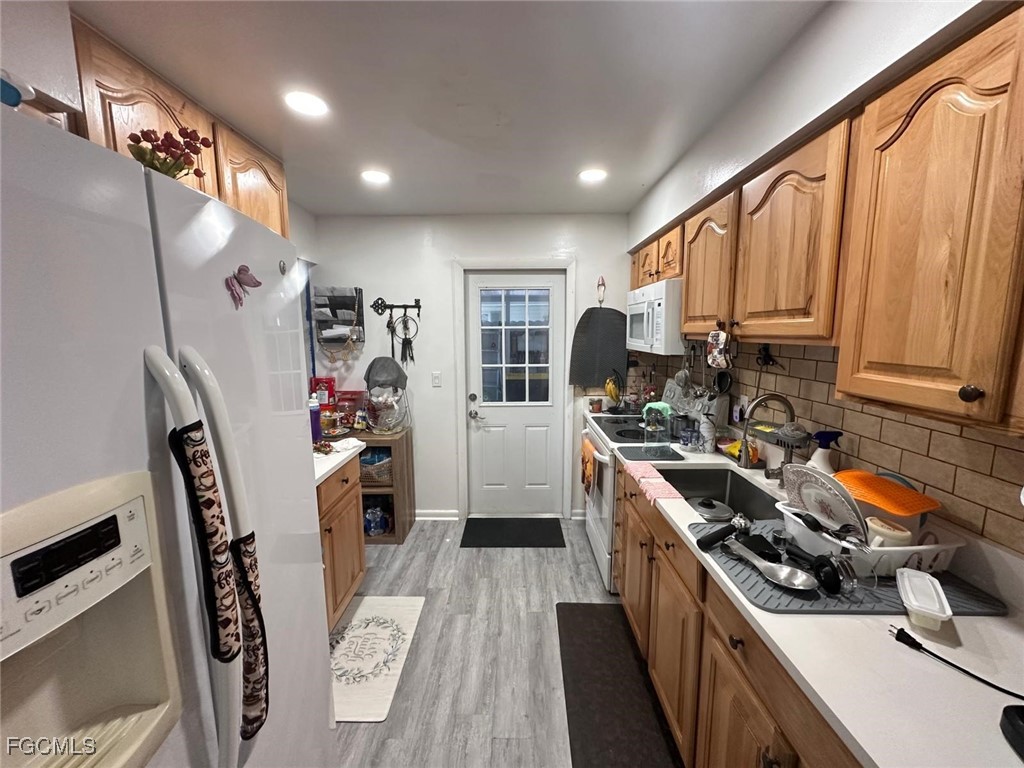 19 Pinewood Boulevard Lehigh Acres, FL 33936 - Photo 7 of 25 a kitchen with refrigerator a stove a sink dishwasher and wooden cabinets