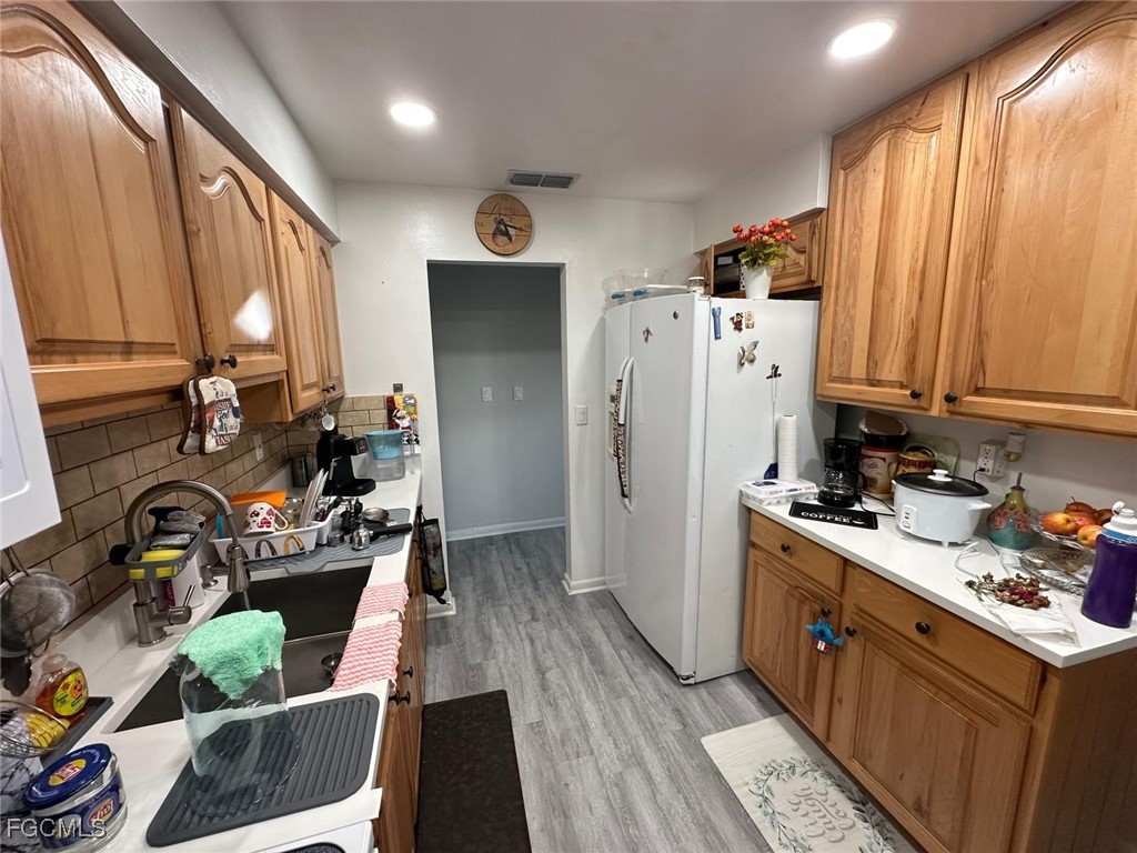 19 Pinewood Boulevard Lehigh Acres, FL 33936 - Photo 9 of 25 a kitchen with stainless steel appliances kitchen island granite countertop a refrigerator a sink dishwasher and a black countertops with wooden floor