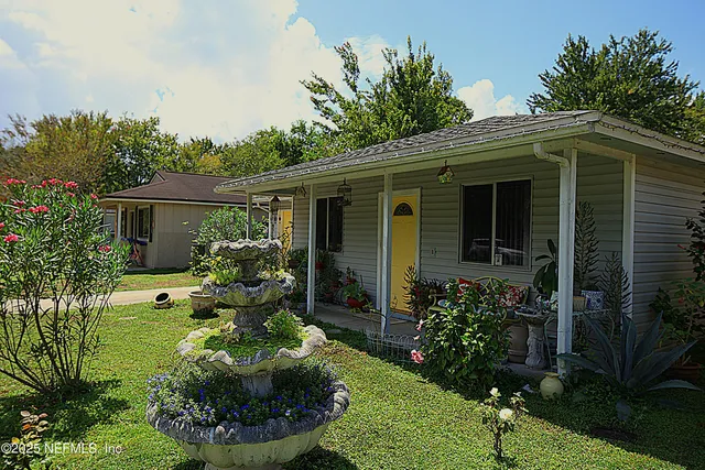 a view of a house with a yard and potted plants