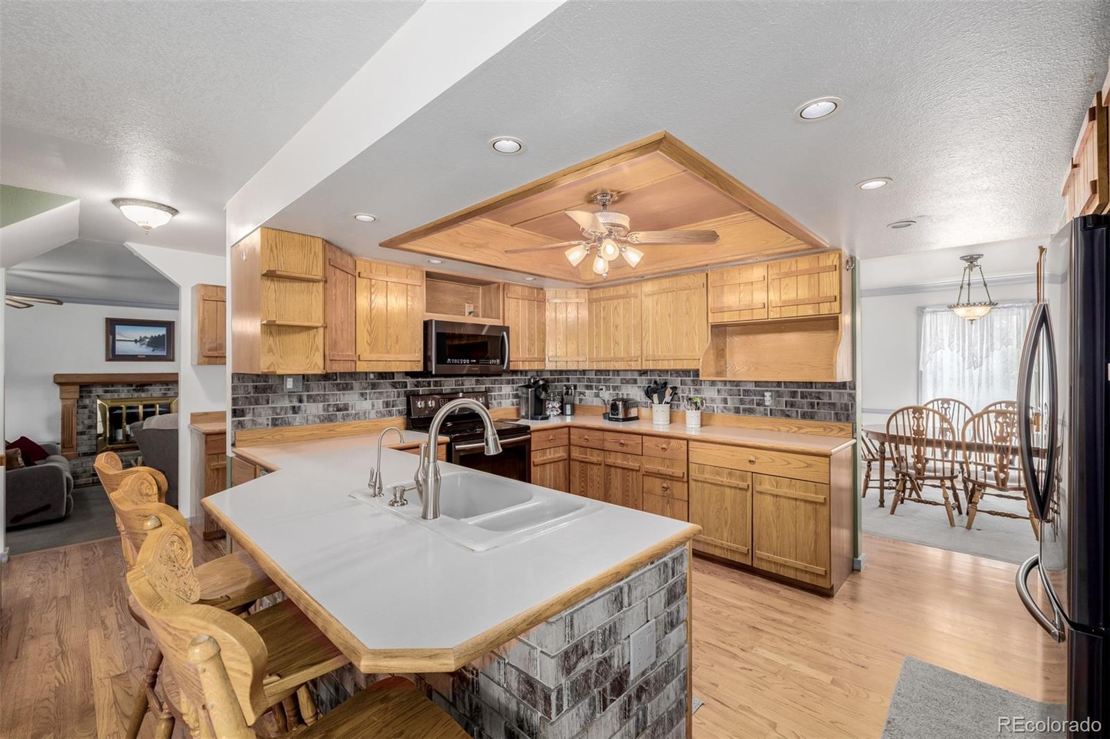 14447 Madison Street Thornton, CO 80602 - Photo 30 of 37 a kitchen with stainless steel appliances kitchen island granite countertop a stove a sink a refrigerator and white cabinets with wooden floor