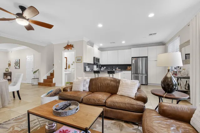 a living room with furniture kitchen view and a chandelier